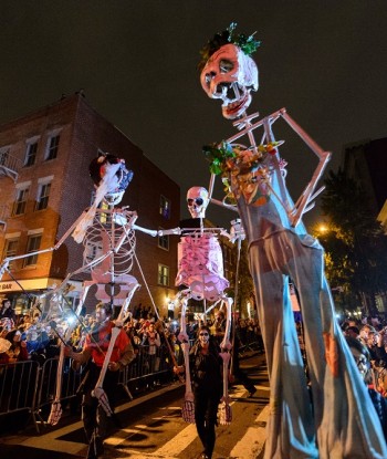 Large skeleton dolls being carried down the street during the Halloween Parade